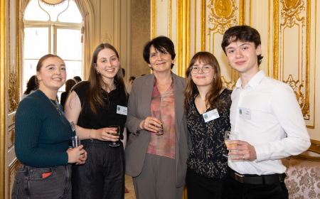 Four alumni posing for a photo with UCD President Orla Feely at a Reception in Paris.
